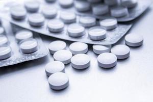 White medical pills are spread on the gray table. photo