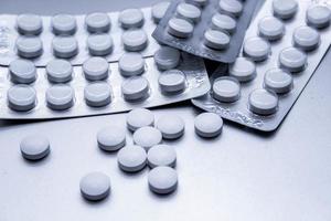 White medical pills are spread on the gray table. photo