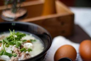 Pork boiled rice with shiitake mushrooms on a black bowl with a spoon on the table. photo