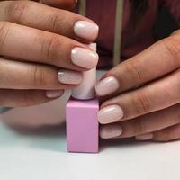 Manicure. Beautiful manicured woman's hands with pink nail polish. Bottle of nail polish. photo