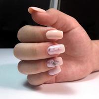 Woman with flesh-colored manicure with design, close up photo