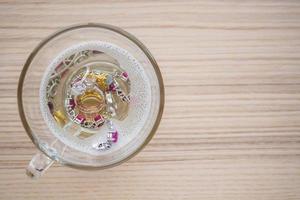 cleaning vintage jewelry diamond ring and bracelet in glass on wood table background photo