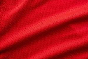 camiseta de fútbol de ropa deportiva de tela roja con fondo de textura de malla de aire foto