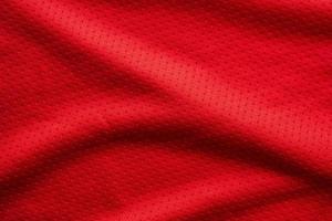 camiseta de fútbol de ropa deportiva de tela roja con fondo de textura de malla de aire foto