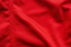 camiseta de fútbol de ropa deportiva de tela roja con fondo de textura de malla de aire foto