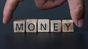 A hand catching the wooden box with money text on the black background, money bank and finance concept photo