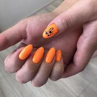 elegante manicura femenina naranja de moda. manos de una mujer con manicura naranja en las uñas foto