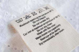 cuidado de la ropa instrucciones de lavado etiqueta de ropa sobre fondo de textura de tela foto