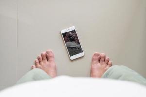 hombre mirando un teléfono móvil con una pantalla de cristal rota en el suelo foto