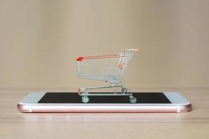 shopping cart on mobile smartphone on wood table photo