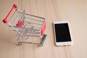 Mobile phone with shopping cart on wood table background shopping online concept photo