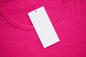 Blank white clothes tag label on new pink shirt photo