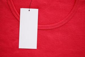 Blank white clothes tag label on new red shirt photo