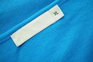 Blank white clothes tag label with XL size on new blue shirt photo