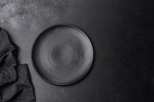 Empty black plate over dark stone background with free space. Top view photo