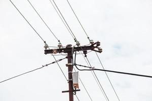 Electric pole power lines outgoing electric wires againts on cloud blue sky. photo