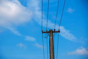 poste eléctrico líneas eléctricas cables eléctricos salientes contra el cielo azul de nubes. foto