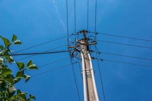 Electric pole power lines outgoing electric wires againts on cloud blue sky. photo