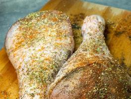 muslos de pavo con especias se encuentran en una tabla de cortar de cocina. carne de ave. la carne jugosa está esperando ser cocinada. esperando el horno. foto