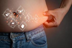 Closeup of asian man catch stomach with jean trousers related vector icon graphic red light, planning exercise and loss weight for good health in the feature, healthcare and gym concept copy space photo