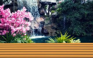 Brown table wooden shelf with pink flowers and waterfall backdrop. photo