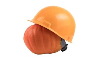 Orange pumpkin in a yellow construction helmet, hard hat on a white isolated background. photo
