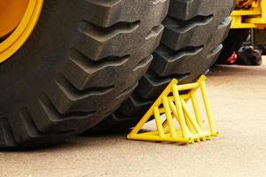 Yellow chock, wheel chock, under the wheel of a mining truck. Brake shoe. Security engineering. photo