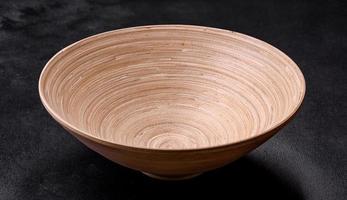 An empty wooden brown fruit bowl on a dark concrete background photo