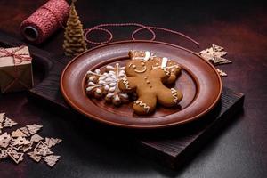 Beautiful gingerbread on a brown ceramic plate with Christmas tree decorations on a dark concrete background photo