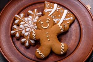 Beautiful gingerbread on a brown ceramic plate with Christmas tree decorations on a dark concrete background photo
