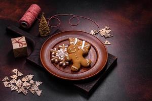 Beautiful gingerbread on a brown ceramic plate with Christmas tree decorations on a dark concrete background photo