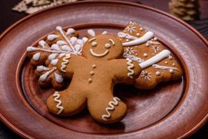 Beautiful gingerbread on a brown ceramic plate with Christmas tree decorations on a dark concrete background photo