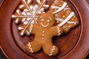 Beautiful gingerbread on a brown ceramic plate with Christmas tree decorations on a dark concrete background photo