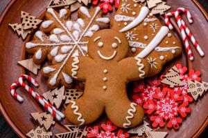 Beautiful gingerbread on a brown ceramic plate with Christmas tree decorations on a dark concrete background photo
