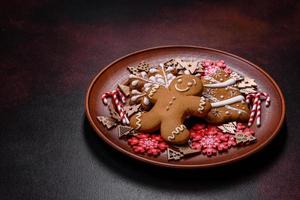 Beautiful gingerbread on a brown ceramic plate with Christmas tree decorations on a dark concrete background photo