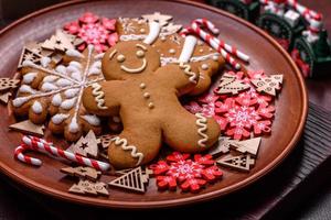 Beautiful gingerbread on a brown ceramic plate with Christmas tree decorations on a dark concrete background photo
