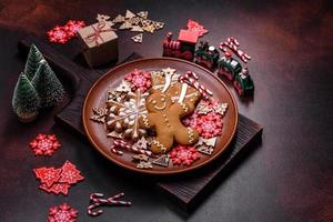 Beautiful gingerbread on a brown ceramic plate with Christmas tree decorations on a dark concrete background photo