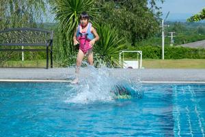 Happy little sisters play in outdoor swimming pool of tropical resort during family summer vacation. Kids learning to swim. Healthy Summer Activities for Kids. photo