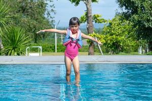 Happy little sisters play in outdoor swimming pool of tropical resort during family summer vacation. Kids learning to swim. Healthy Summer Activities for Kids. photo