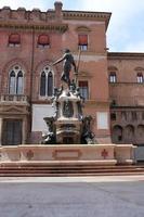 Fountain with nude statue of Neptune and the old palace in Bologna photo