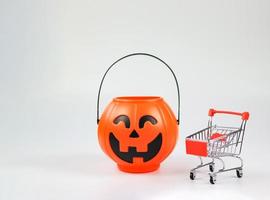 plastic Halloween pumpkin bucket  with shopping cart or trolley isolated  on white  background with copy space. Halloween holiday concept. photo