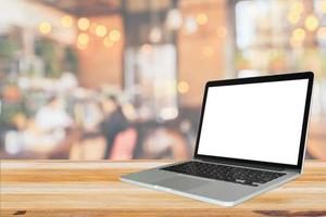 Blank white screen laptop computer on wood table top with cafe restaurant abstract bokeh light defocused blur background photo