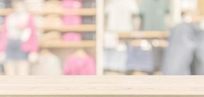 Empty wood table top with modern clothing store interior blur abstract defocused background with bokeh light for product display photo