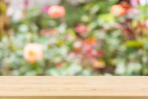 Empty wood table top with abstract blur colorful rose flowers in the garden natural bokeh light background for product display photo