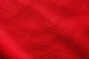 Red fabric sport clothing football jersey with air mesh texture background photo