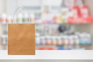 Paper bag on Pharmacy drugstore counter table with medicine and healthcare product on shelves blur background photo