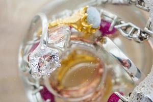 cleaning vintage jewelry diamond ring and bracelet in glass on wood table background photo