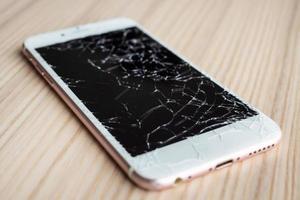 broken glass of mobile phone screen on wooden background photo