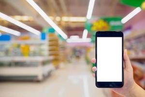 Woman hold mobile phone while shopping in supermarket photo