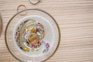 cleaning vintage jewelry diamond ring and bracelet in glass on wood table background photo